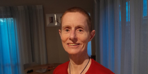 A woman with a shaved head smiling into the camera