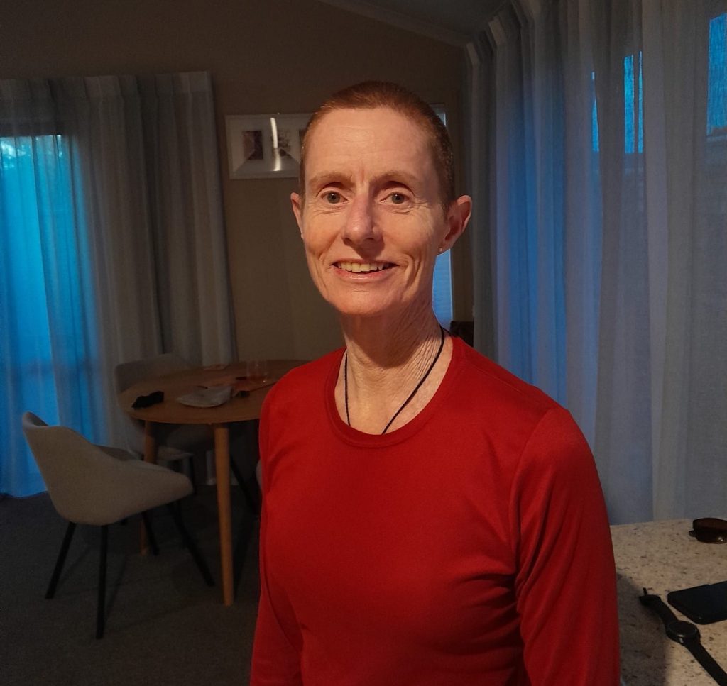A woman with a shaved head smiling in to the camera