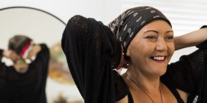 Leondra smiling while tying a head scarf