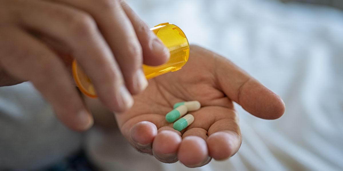 3 pills being shaken from a bottle into someone's hand