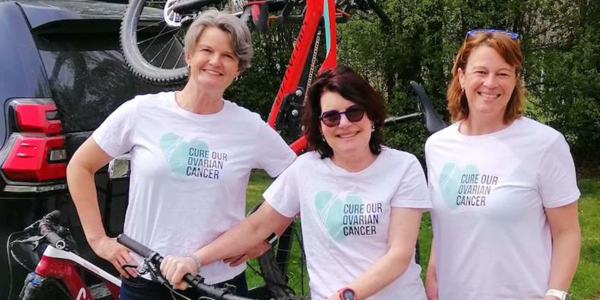 three women standing infront of a car with bikes